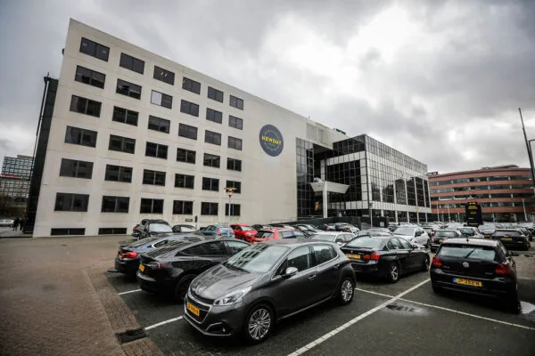 Kantoorgebouw aan de Marten Meesweg met het logo van Newday op de gevel en een volle parkeerplaats op de voorgrond.